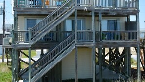 Een houten huis met twee verdiepingen, een balkon en een trap.