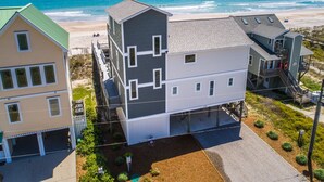 Una proprietà fronte spiaggia con un edificio a due piani, un garage e un piccolo giardino.