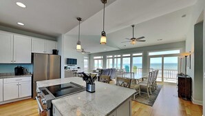 Una cucina moderna con isola centrale, zona pranzo con vista e ventilatore a soffitto.