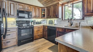 A modern kitchen with wooden cabinets, stainless steel appliances, and a large window providing natural light. - Spectacular 180° Beaver Lakefront Views! Steps to Shoreline+Pool Table+Fire Pit (Garfield)