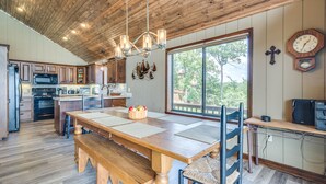 A spacious kitchen with wooden cabinetry, a large dining table, and a view through a window. - Spectacular 180° Beaver Lakefront Views! Steps to Shoreline+Pool Table+Fire Pit (Garfield)