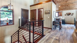 A spacious interior with a wooden staircase, a dining area, and a view of the outdoors. - Spectacular 180° Beaver Lakefront Views! Steps to Shoreline+Pool Table+Fire Pit (Garfield)
