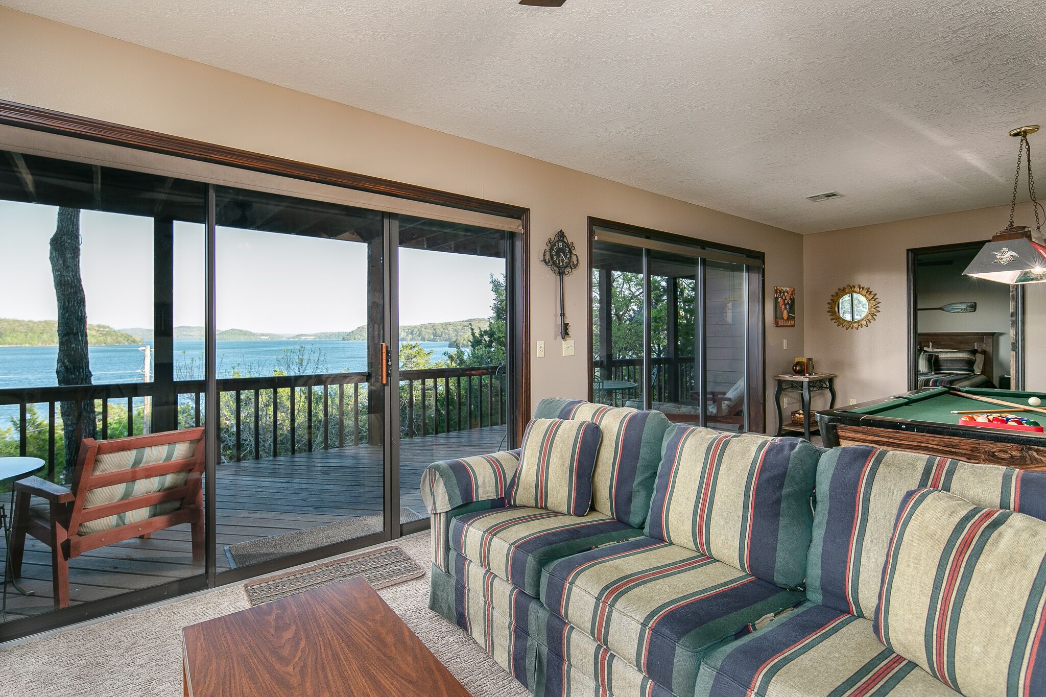 A living room with a sofa, a pool table, and a view of the outdoors.