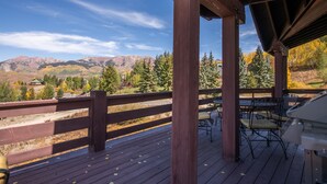 Eine Holzdielen-Terrasse mit Blick auf Berge und Bäume.