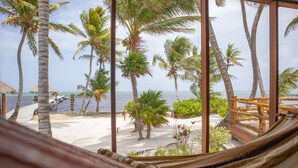 Eine Hängematte in einem Zimmer mit Blick auf einen Strand und Palmen.