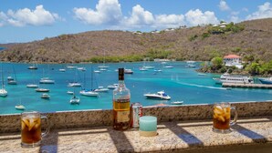 Vista sul litorale con barche, una bottiglia di rum Cruzan invecchiato e una lattina di Coca-Cola Light su un balcone.