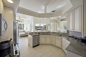 A modern kitchen with a central island, built-in appliances, and a view to the living area.