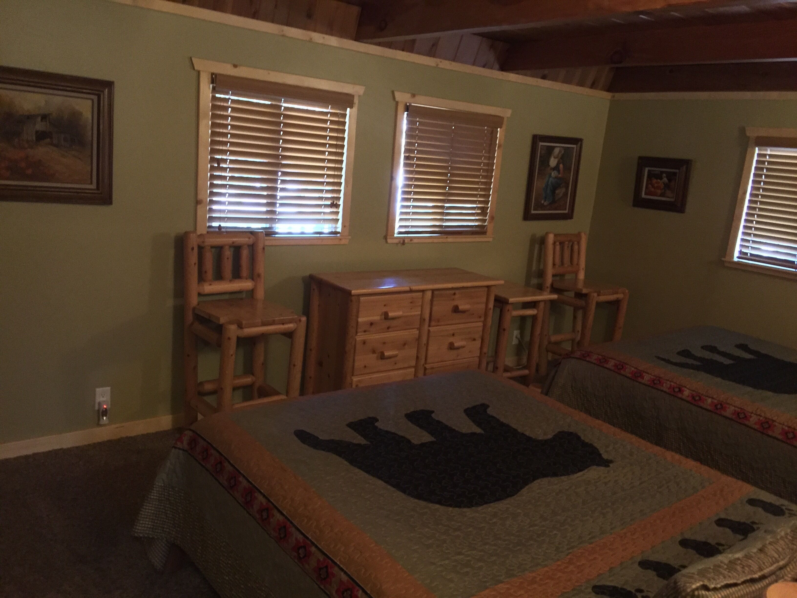 Una habitación con dos camas, muebles de madera y ventanas con persianas.