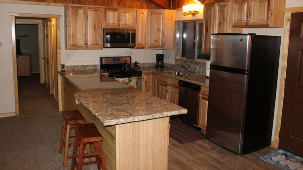A kitchen with wooden cabinets, a granite countertop, a stainless steel refrigerator, and a microwave. - Walking distance to Snow Summit! (Big Bear Lake)