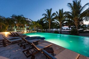 Une piscine avec des chaises longues et des palmiers.