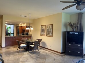 A modern kitchen with a dining area, featuring a central island, pendant lighting, and a ceiling fan.