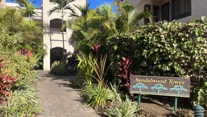 A pathway lined with various plants and a sign reading "Sandalwood Tower". -  The Shores, quiet, upgraded condo, large lanai w/ garden area and lawn  (Waikoloa)