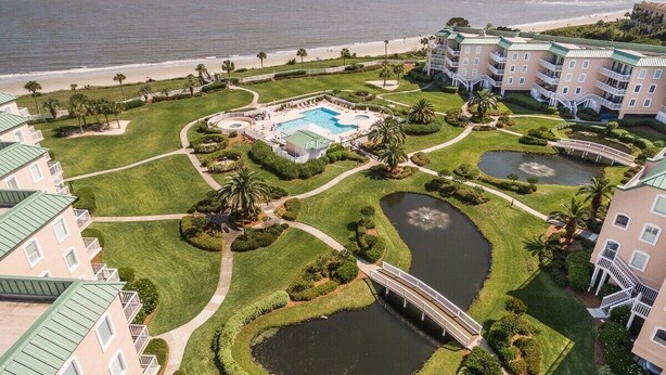 A resort with multiple buildings, a central pool, and several water features. - Luxurious Oceanfront Condominium (St Simons Island)
