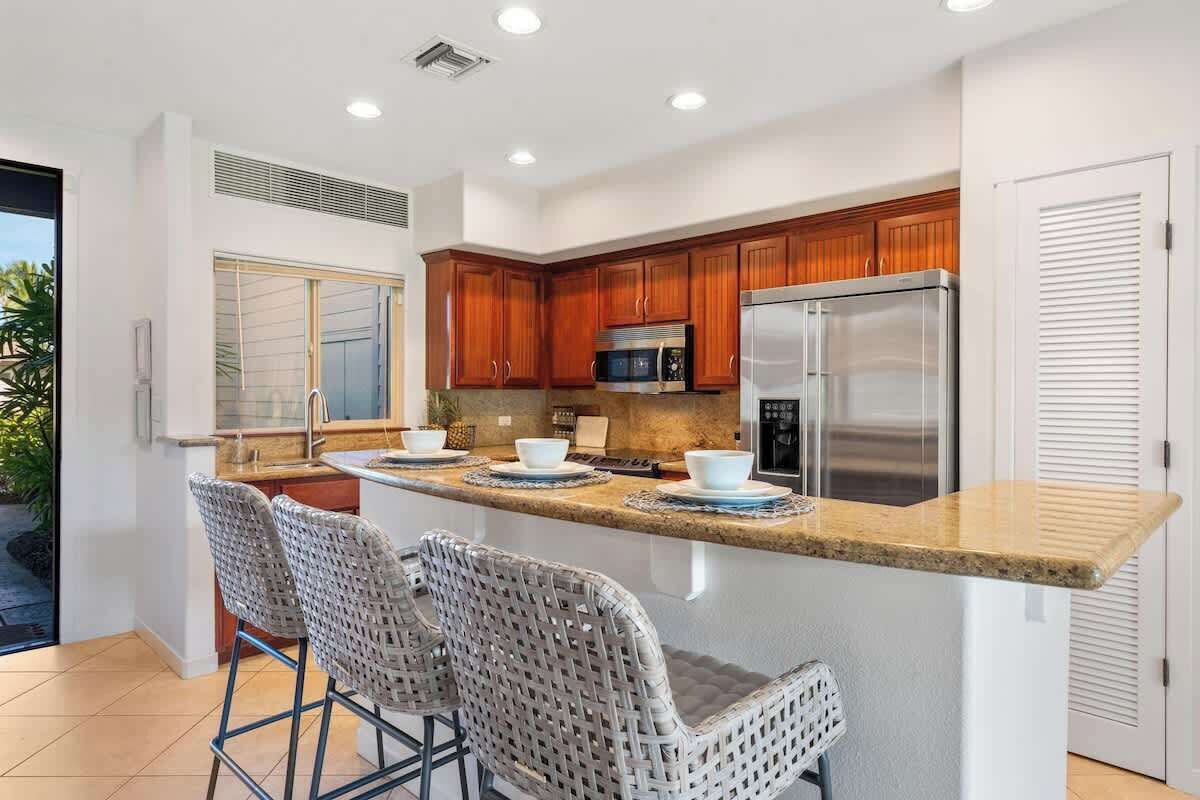 Una cocina moderna con armarios de madera, electrodomésticos de acero inoxidable y una isla central con taburetes de bar.