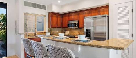 Una cocina moderna con armarios de madera, electrodomésticos de acero inoxidable y una isla central con taburetes de bar.