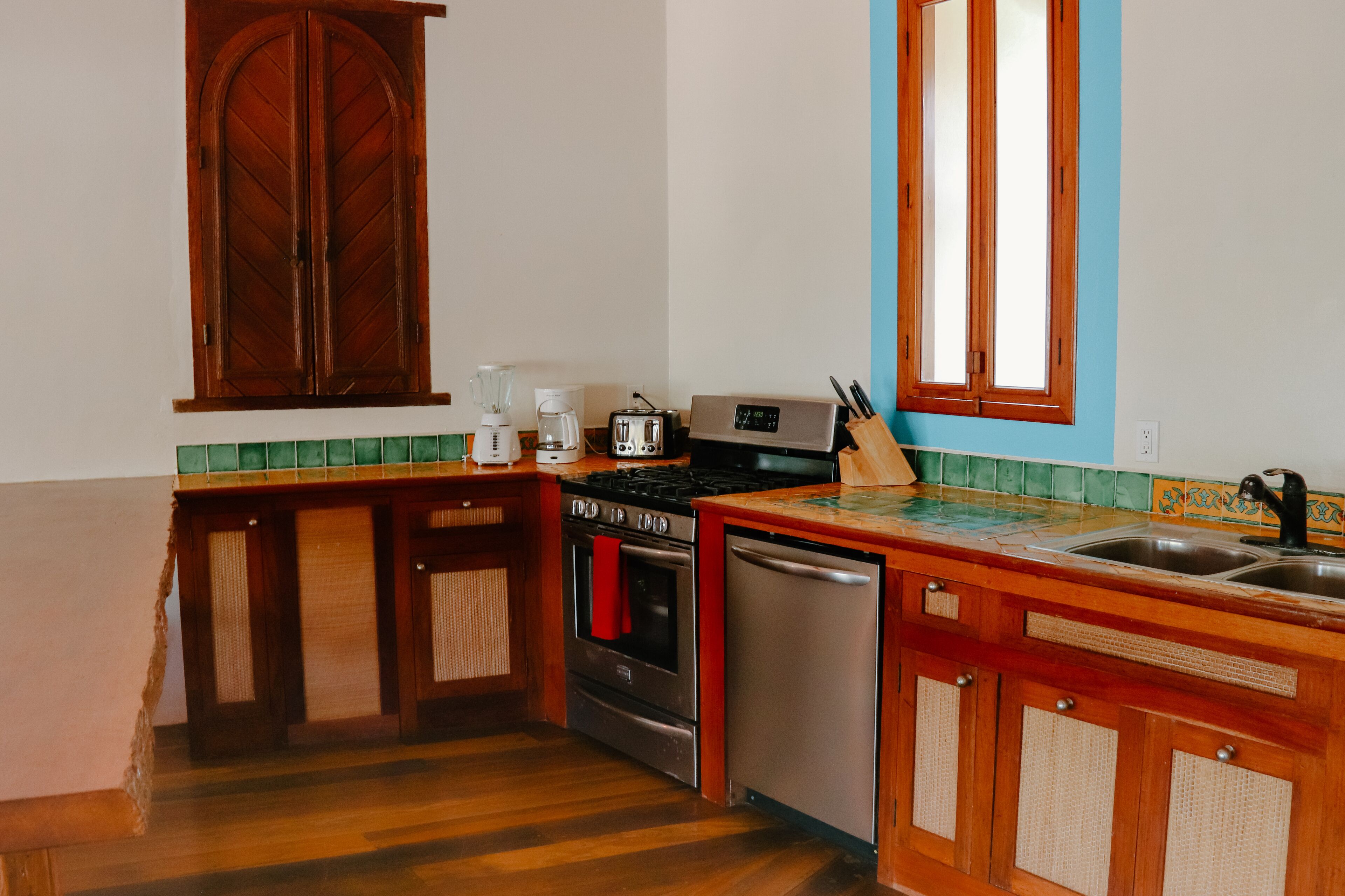 Une cuisine avec des meubles de rangement en bois, une cuisinière, un lave-vaisselle et un évier.