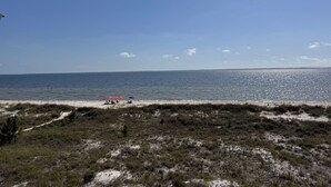 A beach with a clear sky, a sandy shore, and a few umbrellas. - Fully Remodeled 2025 Beachfront Escape- Pet Friendly- Steps to Sand & Gulf Views (St Joe Beach)