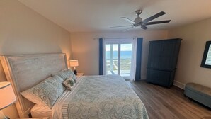 A bedroom with a bed, a nightstand, a lamp, a ceiling fan, a view of the outdoors, and a wardrobe. - Fully Remodeled 2025 Beachfront Escape- Pet Friendly- Steps to Sand & Gulf Views (St Joe Beach)