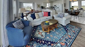 A spacious living room with a large sofa, a coffee table, and a patterned rug. - You’re The Tops | Oceanfront, Amazing Views! (Surf City)