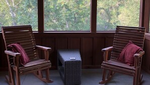 A porch with two wooden rocking chairs, a woven basket, and a patterned rug.