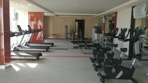 Une salle de sport équipée de tapis de course, de vélos d’appartement et d’appareils de musculation.