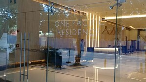 Un espace d’accueil moderne doté d’une façade en verre, d’un comptoir de réception et d’un coin salon avec des chaises et des tables.