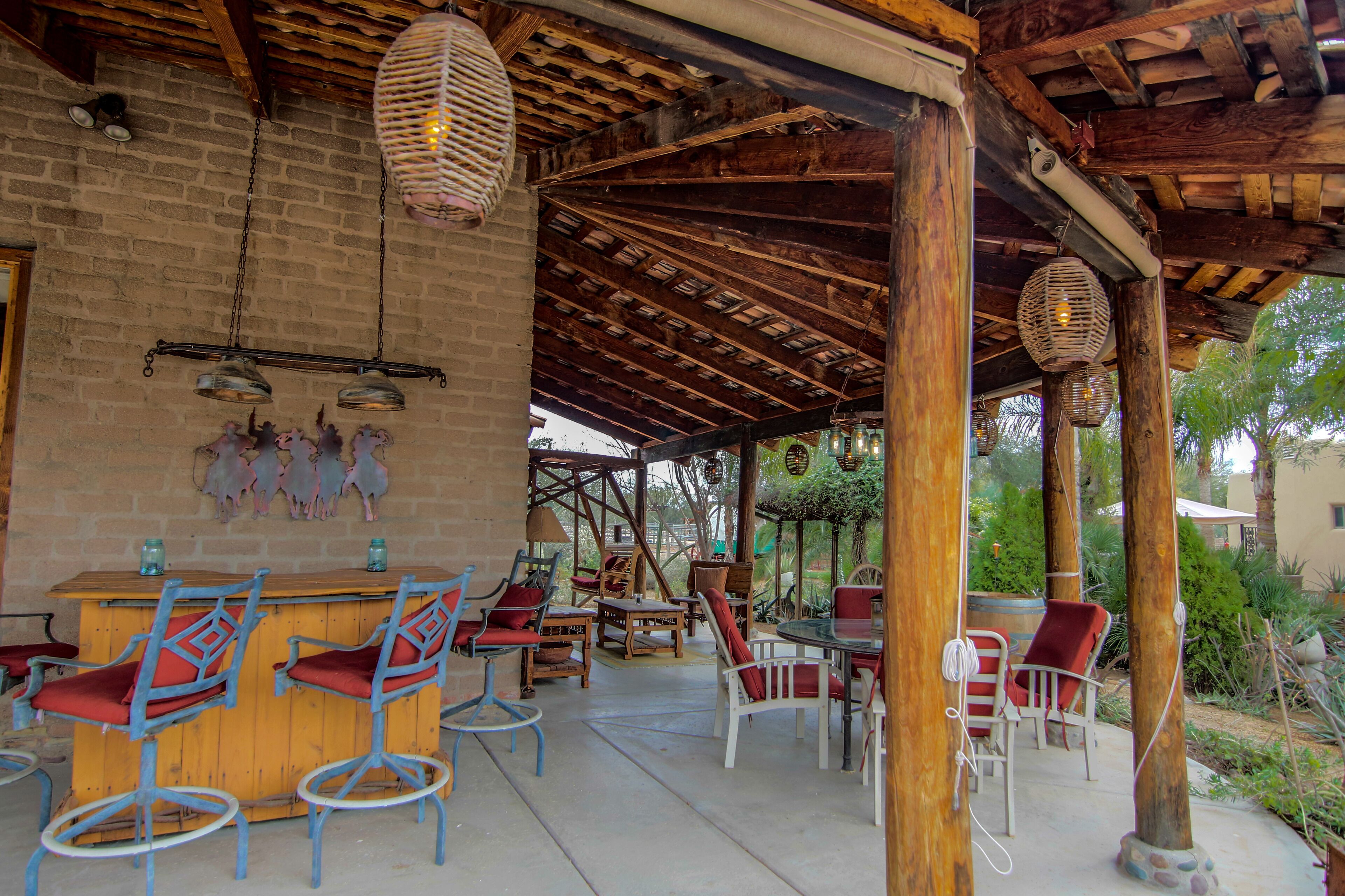 An outdoor patio area with wooden furniture, hanging lanterns, and a brick wall.