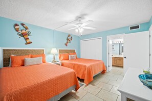 A room with two beds, a ceiling fan, and a bathroom visible through an open door. - Beachfront | 1st Floor Condo | Mariner West | Pool (Panama City Beach)