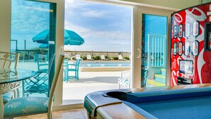 A pool area with chairs and umbrellas, a pool table, and a Coca-Cola vending machine. - Beachfront | 1st Floor Condo | Mariner West | Pool (Panama City Beach)