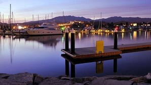 En lystbådehavn i skumringen med både i havnen, roligt vand og en dok med en gul stol.