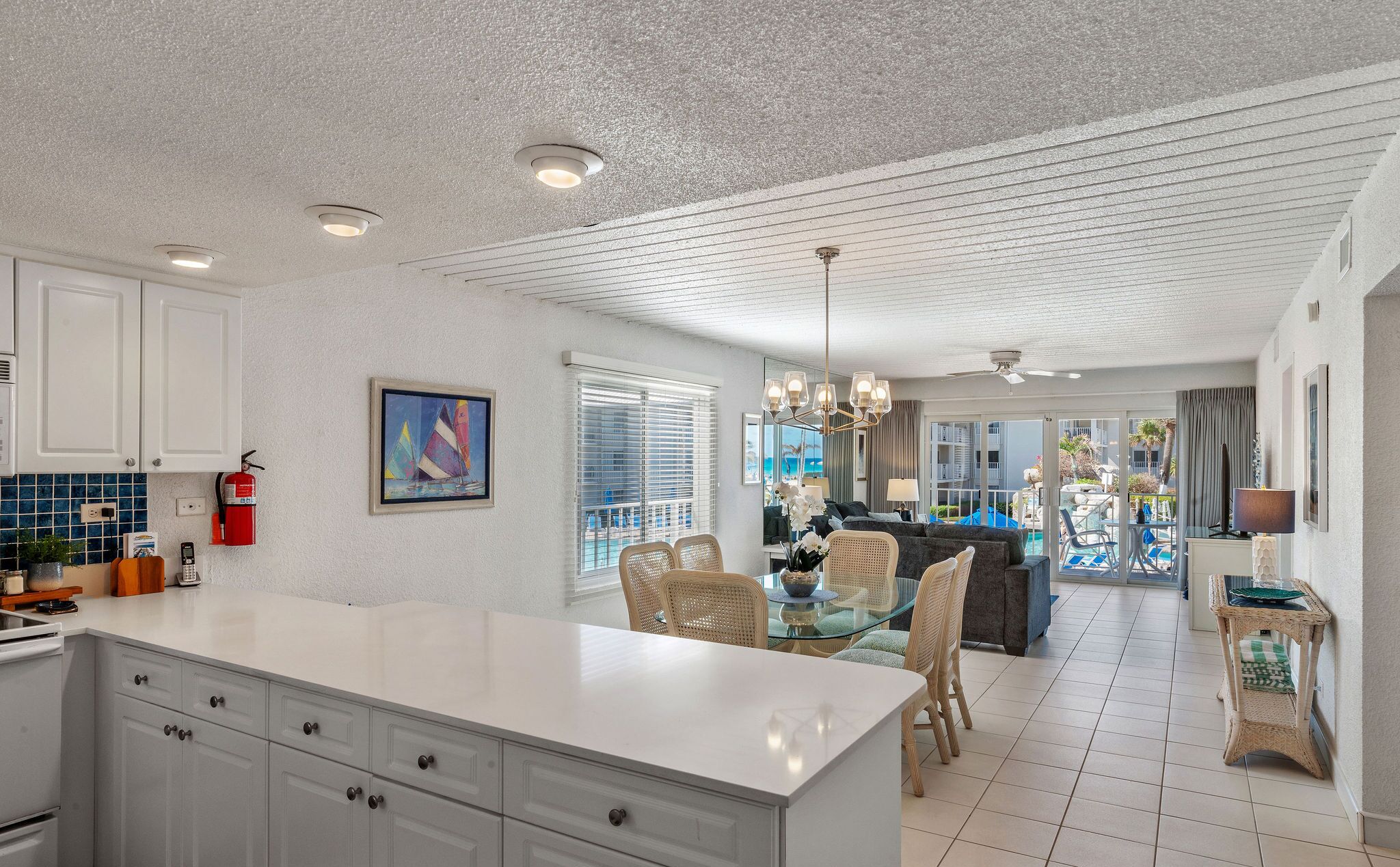 A spacious kitchen with a large island, white cabinetry, and a view of the pool area.