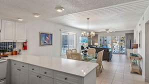 A spacious kitchen with a large island, white cabinetry, and a view of the pool area.