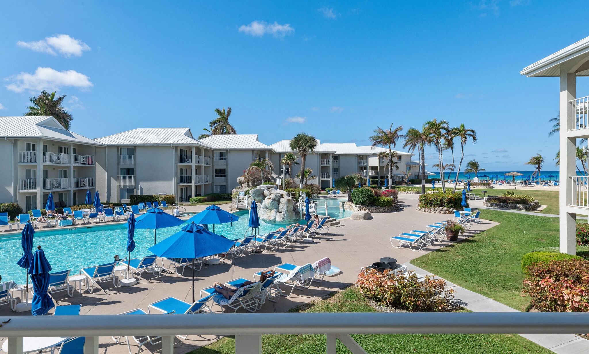 Un resort con piscina, sillas de descanso y palmeras.