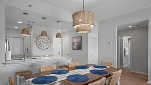 A dining area with a wooden table, wicker chairs, and a woven pendant light. - Tops'l Resort Beach Manor Ocean Blue Chic Condo! Beachfront with private beach! (Miramar Beach)