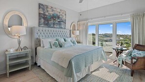 A bedroom with a large bed, a ceiling fan, a view of the landscape, and a balcony with a chair. - Tops'l Resort Beach Manor Ocean Blue Chic Condo! Beachfront with private beach! (Miramar Beach)