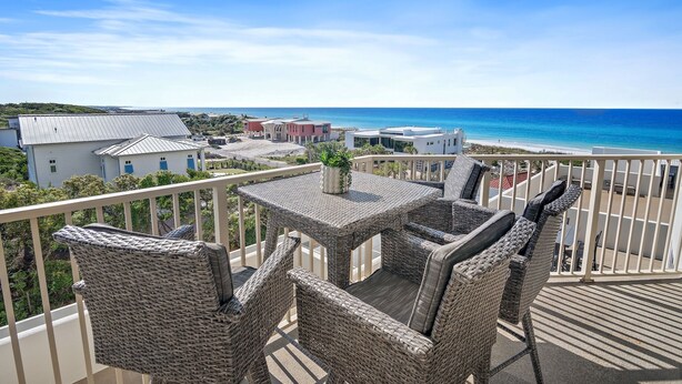 A balcony with wicker furniture and a view of the beach and ocean. - Tops'l Resort Beach Manor Ocean Blue Chic Condo! Beachfront with private beach! (Miramar Beach)