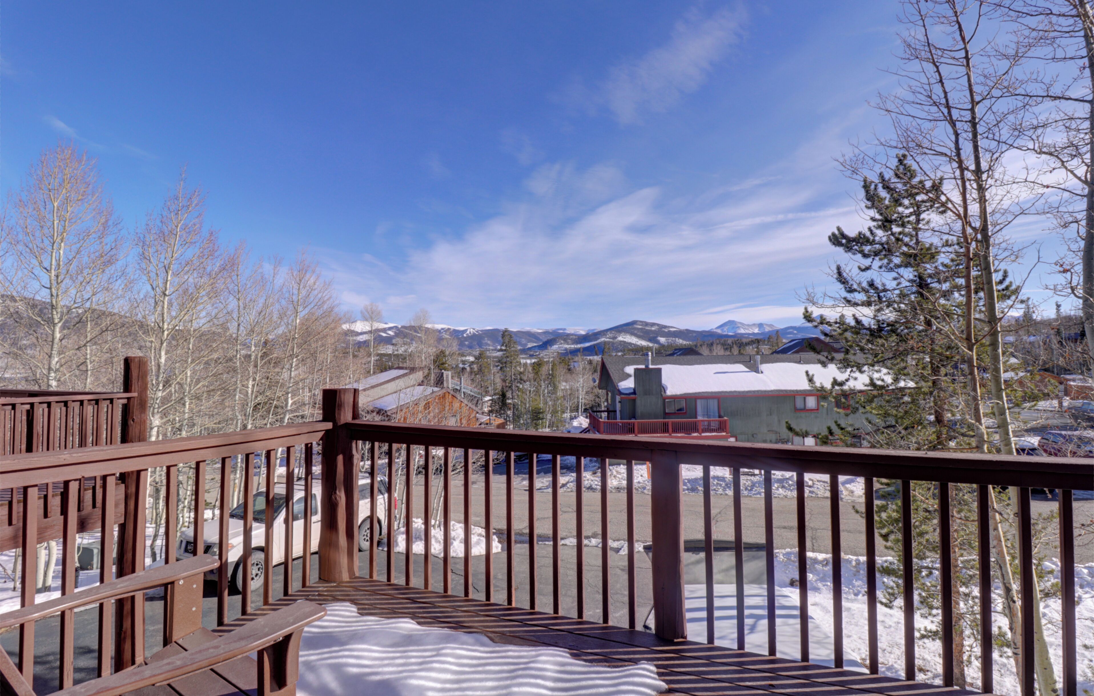 A wooden deck with a view of a snowy landscape and mountains in the background.