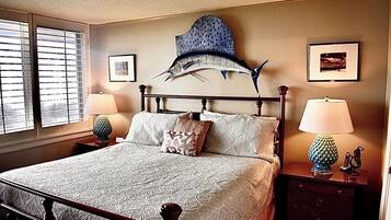 Une chambre à coucher comprenant un lit, deux tables de chevet, une sculpture de poisson fixée au mur et deux tableaux encadrés.
