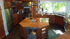 A modern kitchen with a central island, stainless steel appliances, and a large window providing natural light. - Riverfront Lodge great setting, walk to downtown! (Bend)