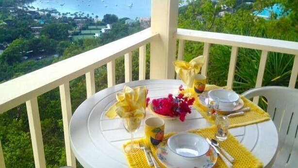A table set on a balcony overlooking a coastal view with boats and greenery. - Tropical Orchid-Just For Two-WINTER STORM SALE- Hot Tub (Cruz Bay)