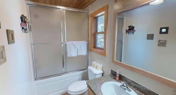 A bathroom with a glass-enclosed shower, a toilet, a sink, and a large mirror.