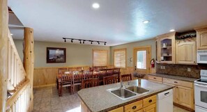 A kitchen with granite countertops, wooden cabinets, and a dining area with wooden chairs and a table.
