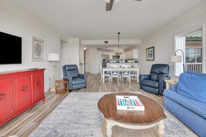A living room with a red cabinet, two leather chairs, a blue sofa, and a wooden coffee table.