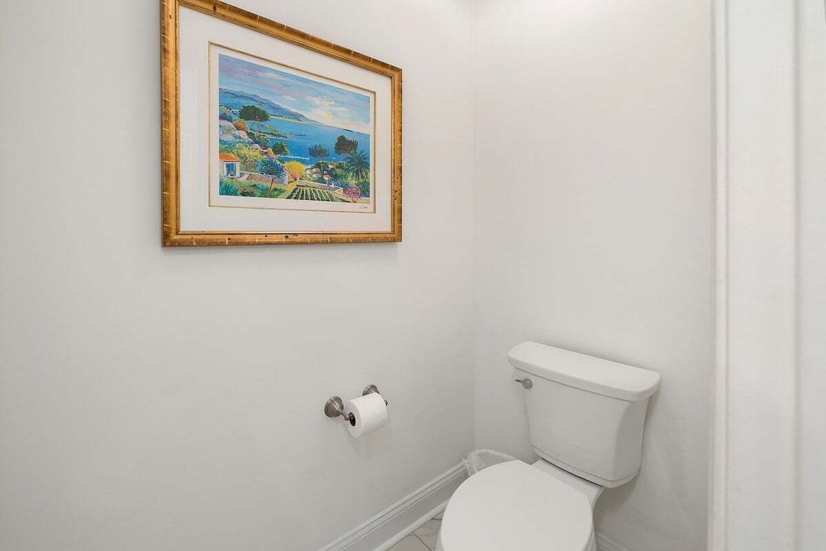 Un baño con un inodoro, un cuadro en la pared y un rollo de papel higiénico.