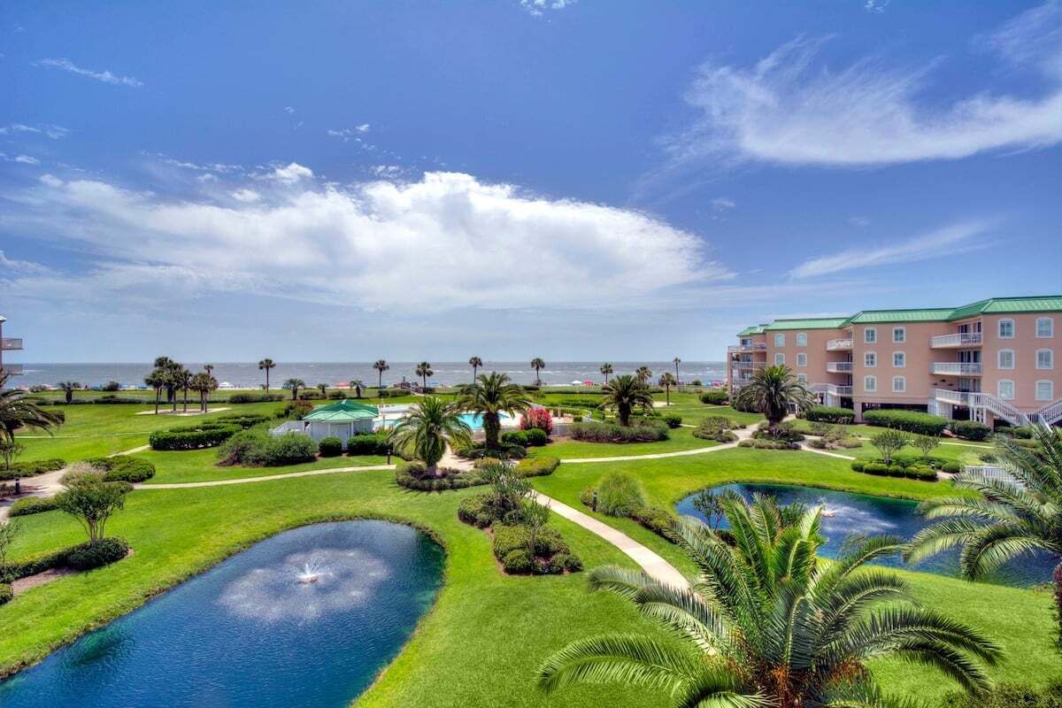 A resort with a pool area, palm trees, and a view of the ocean.