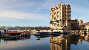 Un hotel di grandi dimensioni con numerosi balconi, una marina piena di barche e un riflesso limpido nell'acqua.