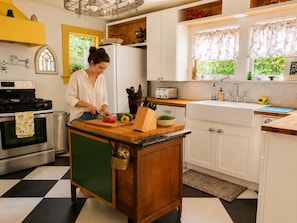 Une cuisine avec un îlot central, une cuisinière, un évier et une fenêtre avec des rideaux.