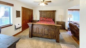 A bedroom with a wooden bed, a ceiling fan, and a window with blinds.