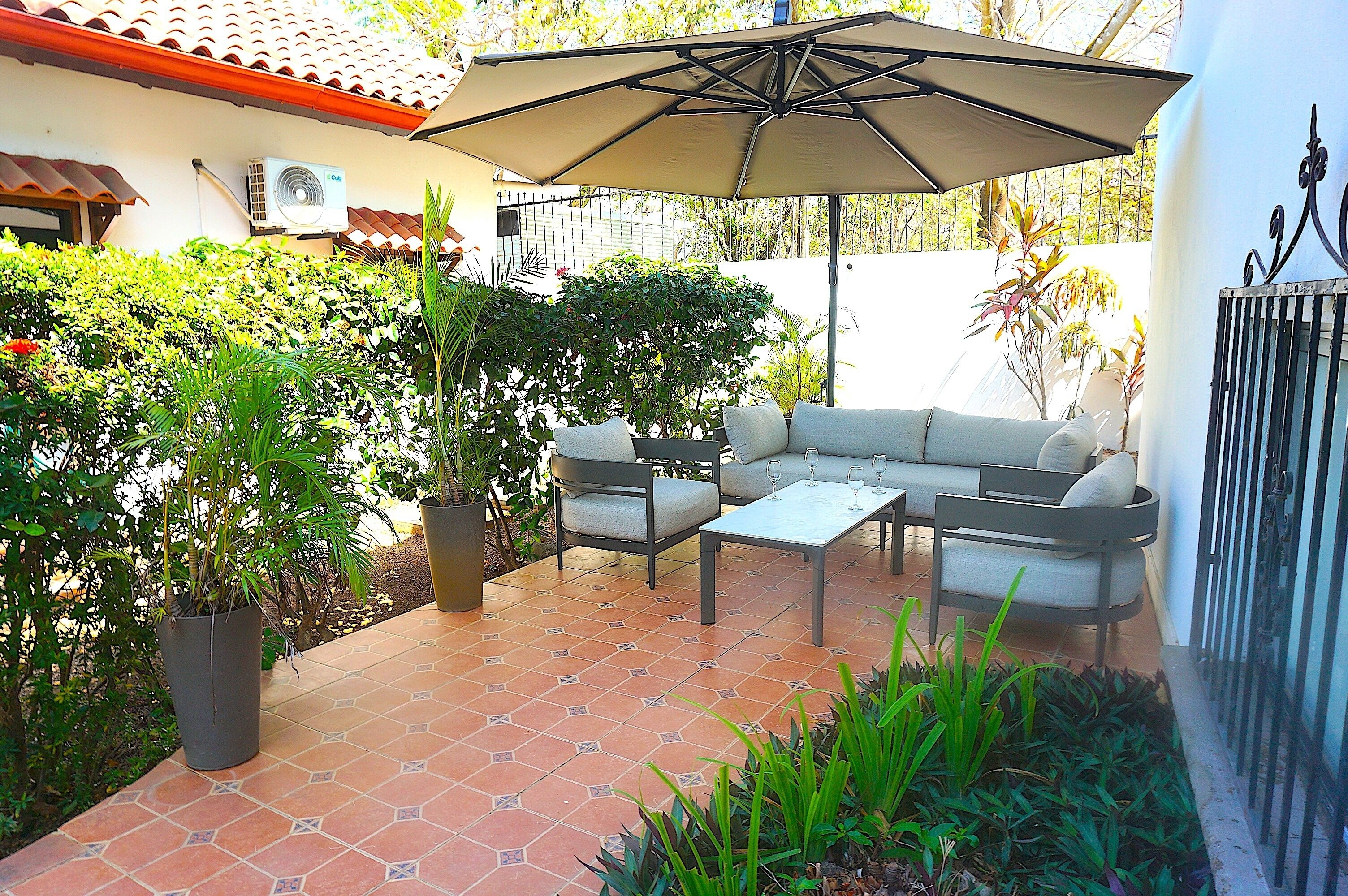 An outdoor patio with a sofa set, a table, and an umbrella.