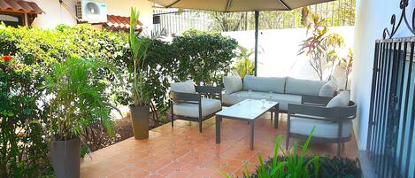 An outdoor patio with a sofa set, a table, and an umbrella.